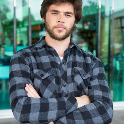 serious-young-man-standing-outdoors-with-his-arms-crossed